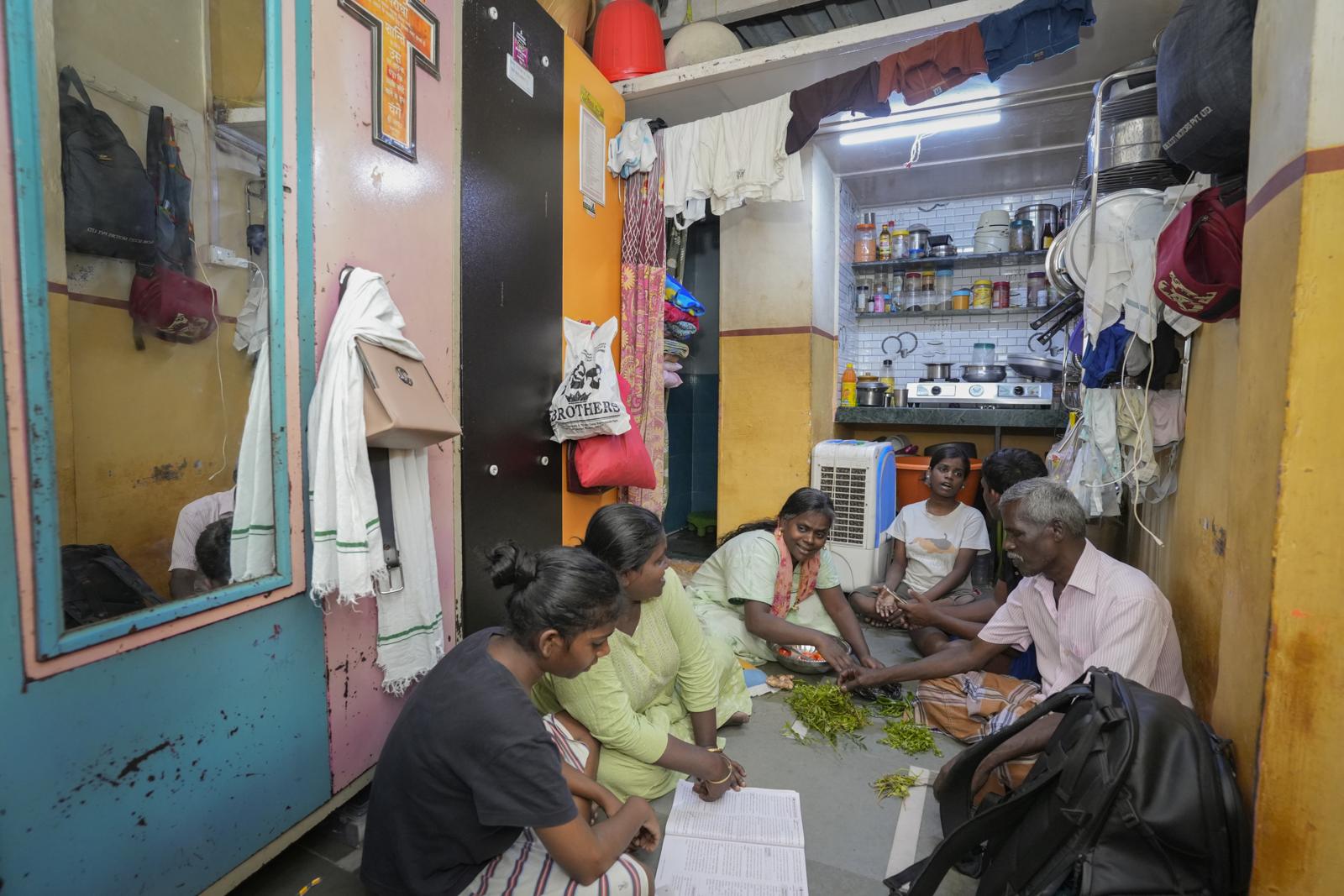 Several women seated on the floor of a small home with a health worker, looking through papers